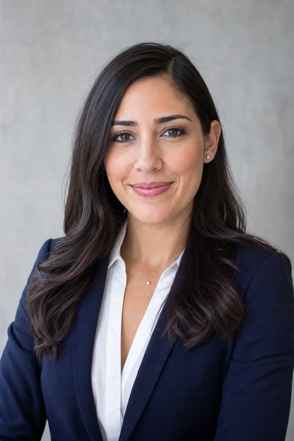 A polished professional corporate headshot of a woman in a navy blazer